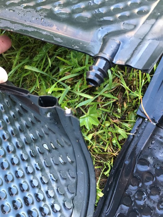 Närbild av poolvärmemattor med kopplingsdetaljer på vått gräs.
