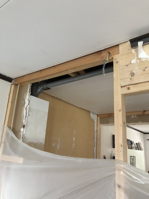 Träreglar och balk som förstärker takstruktur under en renovering, med skyddad möbel i förgrunden.