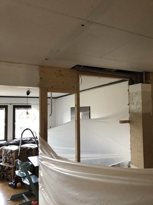 Renoveringsprojekt där en bärande vägg tagits bort i en bostad, med förstärkt balk och plastskydd.