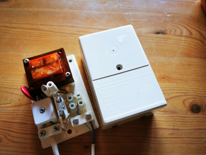 Elektrisk anordning kopplad till telefonledning, möjlig åskskydd, på träbord.