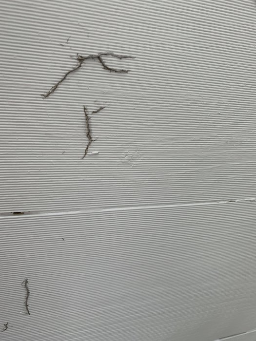 Vitmålade träspont med sprickor och skador i taksprånget uppkomna efter målning.