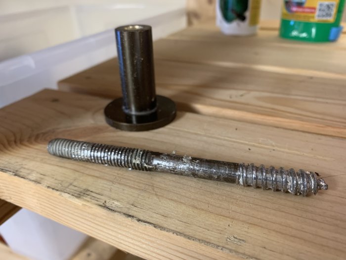 En 10mm diameter skruv ligger på ett träbord framför en annan skruv med cylindrisk hatt vilket illustrerar problemet med infästning i gips.