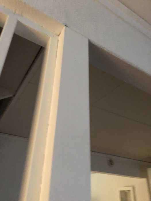 Närbild av en vita dörrkarmar och väggdetaljer som visar upp sammankoppling och struktur för jämförelse av bärighet.