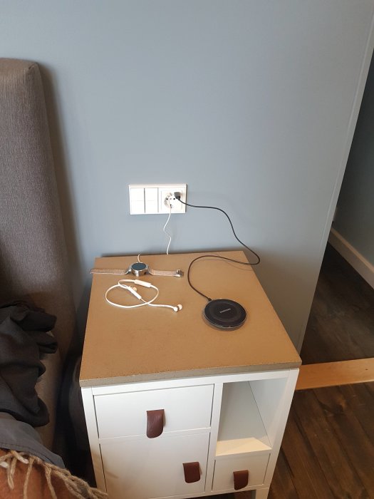 Vägg med KNX-kontrollpanel och laddade enheter på nattduksbord i nyrenoverat sovrum.