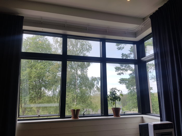 Nytt sovrum med stort hörnfönster utan mörkläggning, utsikt mot grönska.