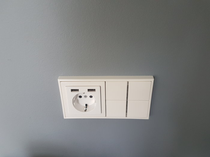 Eluttag och KNX-styrknappar på en ljusgrå vägg