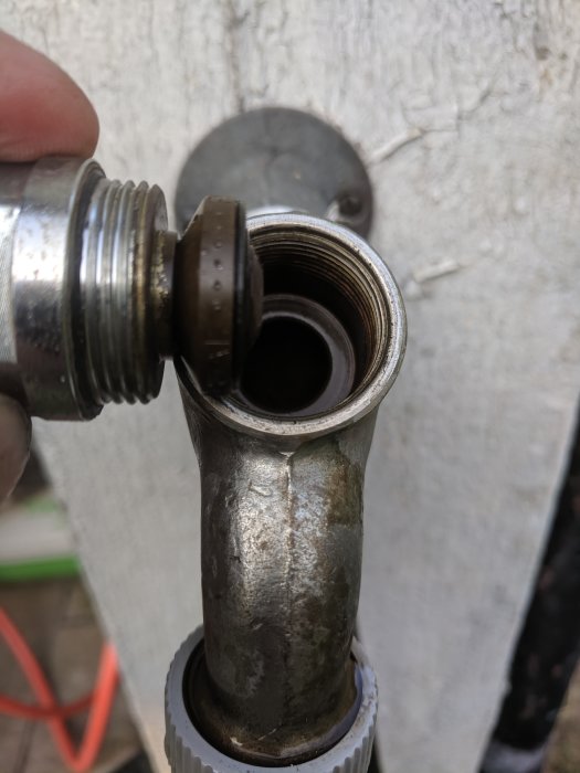 Närbild på öppen ventil och packning med synlig rörgänga, något smutsad, mot vit bakgrund.