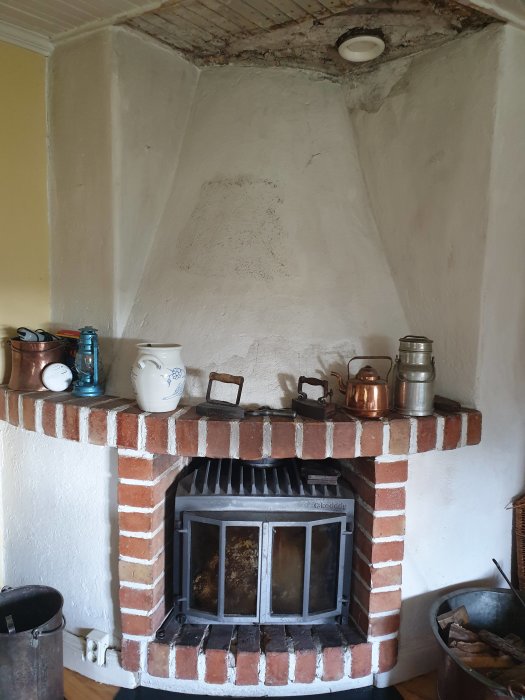 Slitet tegeltak över en kamin med sprickor och fläckar på den vita putsade väggen, behöver reparation.
