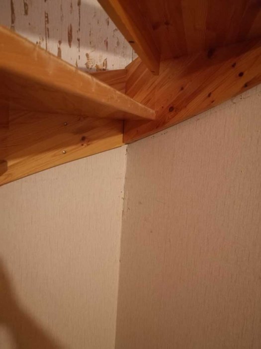 Trappa med hemsnickrad lösning, brädor inkilade mellan trappsteg och vägg, med synliga skruvar.