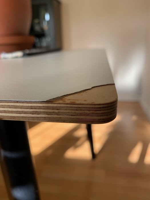 Skadat hörn på matbordsskiva av högtryckslaminat med OSB-underlag.