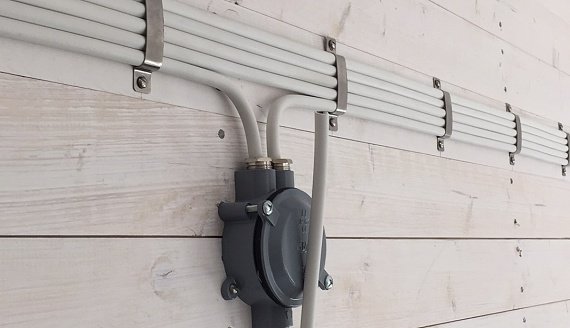 Exempel på prydligt installerade utanpåliggande ledningar och kopplingsdosa på en vit vägg.