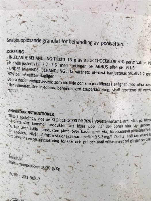 Närbild av instruktioner för dosering av snabbupplösande klorgranulat för poolvatten på en fläckig vit bakgrund.