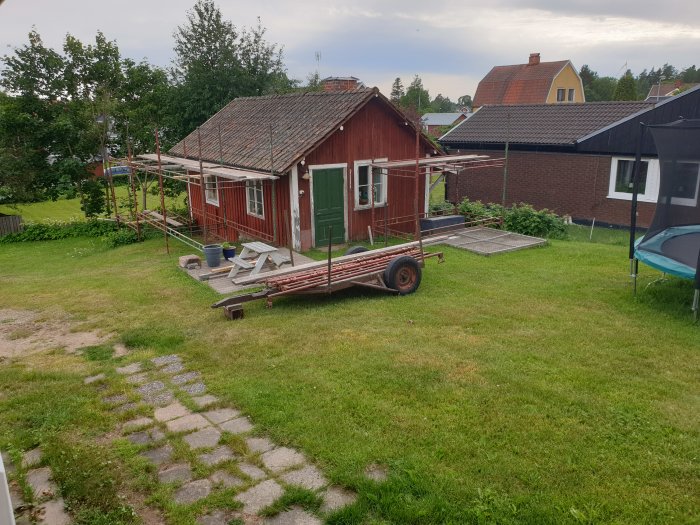 Ställning monterad utanför röd trästuga för byggprojekt på första semesterdagen.