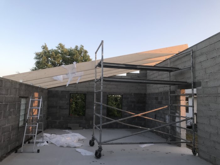 Process med byggnation av takstolar på ett garage, med balk, hammarband och byggställning synliga.