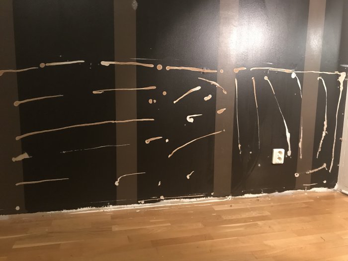 Gipsvägg med borttagna bröstpaneler visar kvarvarande vita limrester och skadat ytskikt.