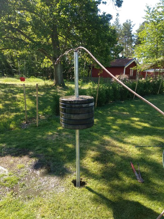 Borrningsutrustning med ett rör och en 90kg vikt i en trädgård för att borra en brunn 5 meter ner.