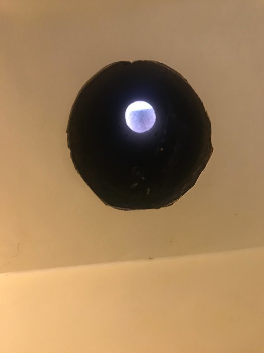 Öppet ventilationsrör i tak med utsikt till skorstenstakplåten.