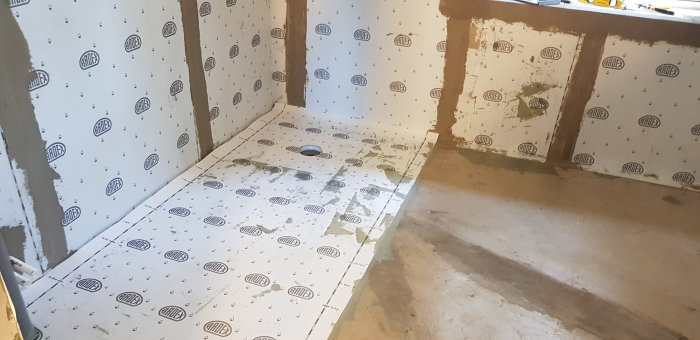 Nyinstallerad Ardex 7+8 tätning och duk på golv med utskuret hål för brunnsmanschetten i ett pågående byggprojekt.