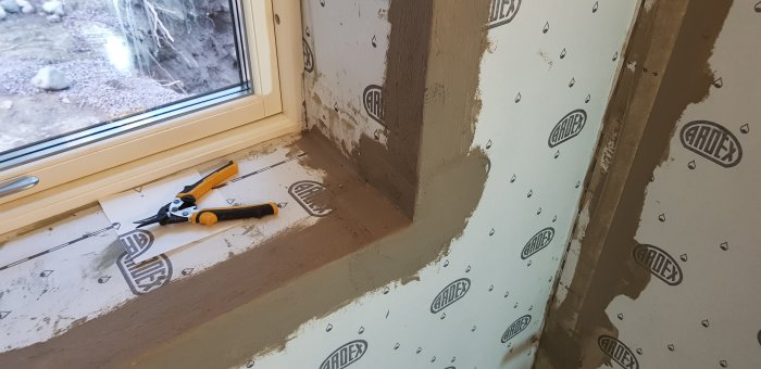 Tätning av fönster med Ardex 7+8 och verktyg på fuktspärrad golvyta nära genomföring.