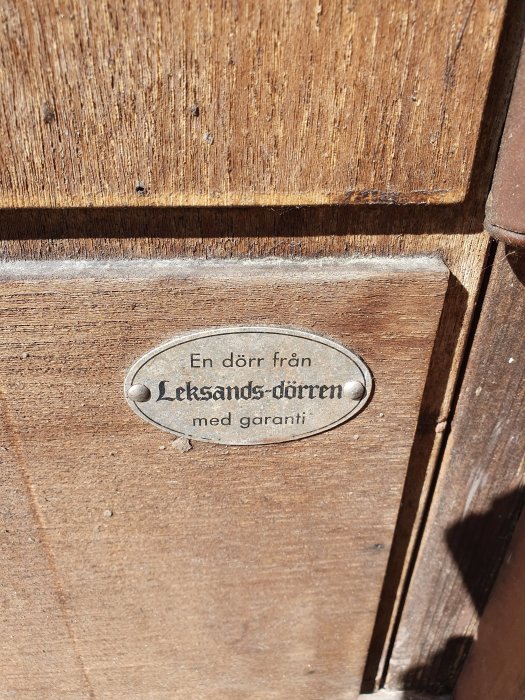 Närbild på en träytterdörr med ett märke från Leksandsdörren och texten "med garanti".
