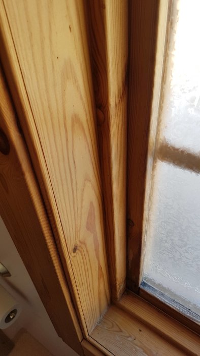Träfönsterkarm med tecken på fuktskador nära fönsterblecket i ett fritidshus.