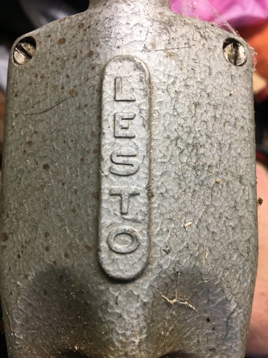 Närbild av ett slitet metallföremål med texten "LESTO" i relief.