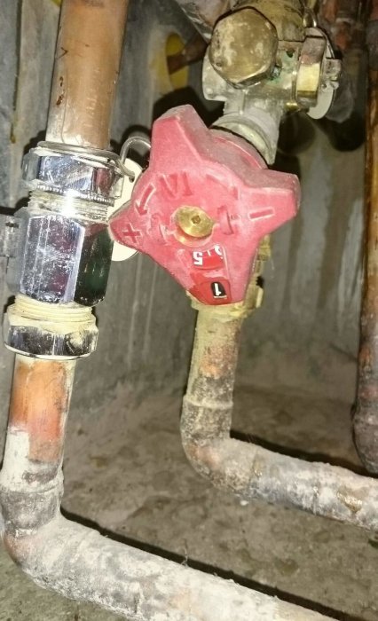 Bild på en röd ballofix ventil på ett vattenrör, tros vara felaktig för avstängning av köksvatten.