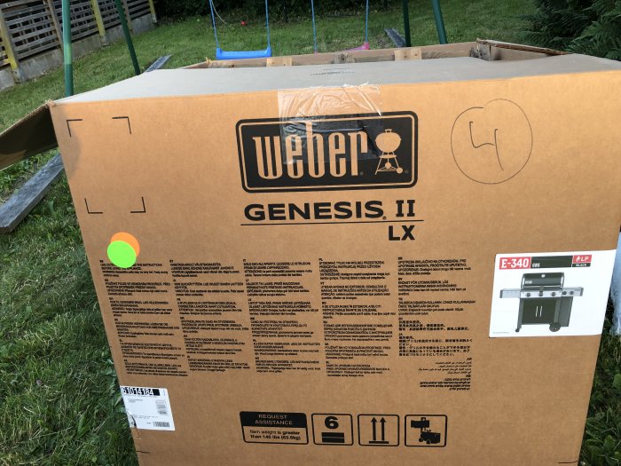 Stort paket med Weber Genesis II grill märkt med Bauhaus logotyp och modellspecifikationer.