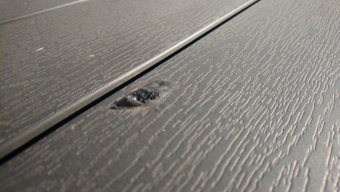 Bränd skada på grått "nonwood" utebord orsakad av vinglas som förstoringsglas i solen.