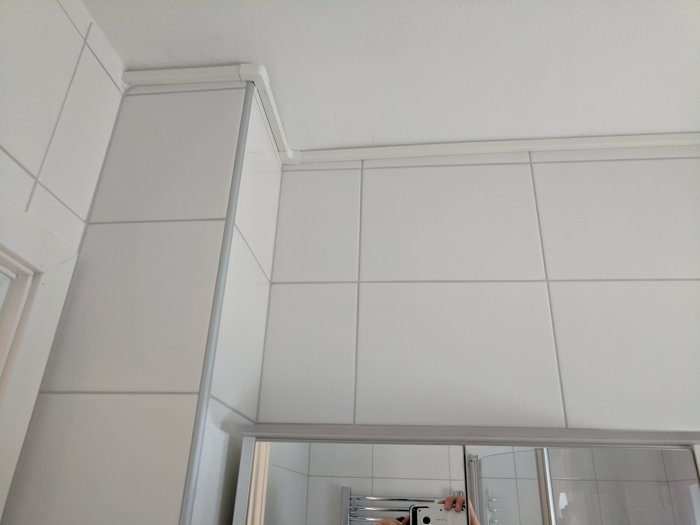 Electrical conduit elegantly installed along the tile wall and ceiling corner.