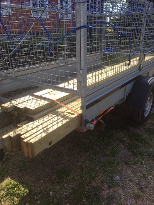 Virke lastat på släpvagn för att bygga klart en uteplats med staket och pergolatak.