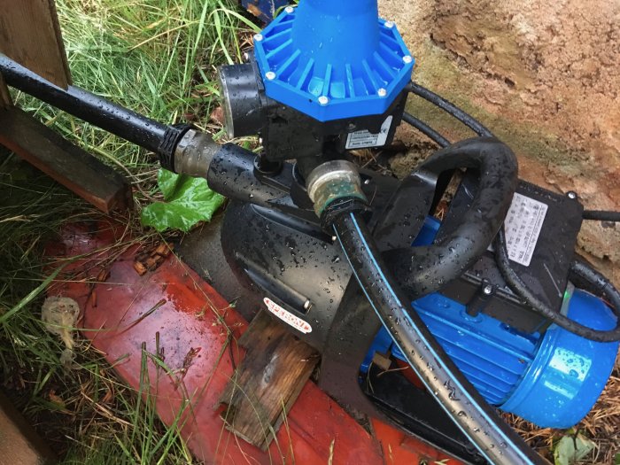 Blå och svart vattenpump ansluten med en ny mässingskoppling i ett utomhusmiljö.