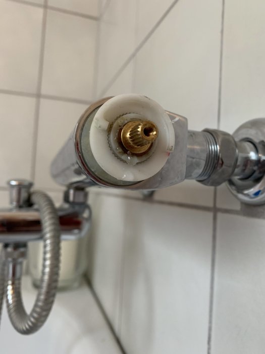 Närbild på en demonterad duschventil med en sliten mässingdel som orsakar läckage.