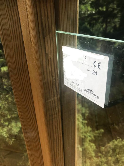 Närbild av ett nyligen installerat räcke med impregnerade trästolpar och lamellglas utan klämfästen.