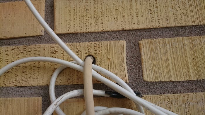 Elektrisk kabel genomförning i en gul dörrkarm med ett uttag på en tegelvägg.