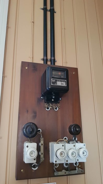 Gammal elektrisk installation med strömbrytare och elmätare på vägg från 1920-talet.