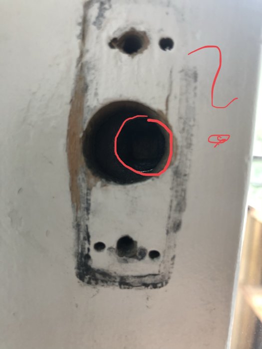 Närbild av ett hål i vägg med markerad kant och frågetecken, antyder fråga om borrning.
