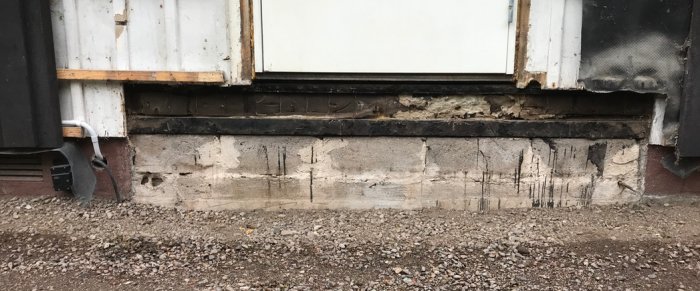 Renoverad fasad med borttagen betongtrappa, exponerad grund och vägg utan lockpanel.