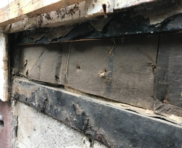 Skadad väggkonstruktion där lockpanel tagits bort, visar isolering och reglar.