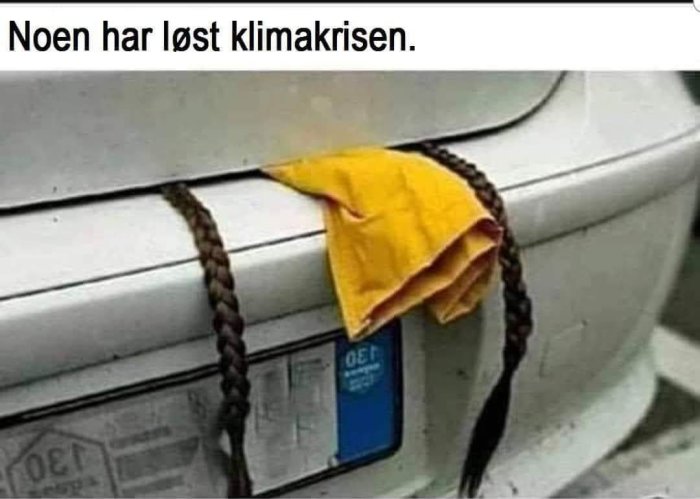 Bilbensinlock med flätor och gult tyg, humoristisk text "Noen har løst klimakrisen.