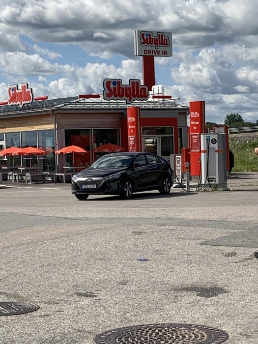 Hyundai Ioniq Electric parkerad framför Sibylla drive-in under solig himmel.