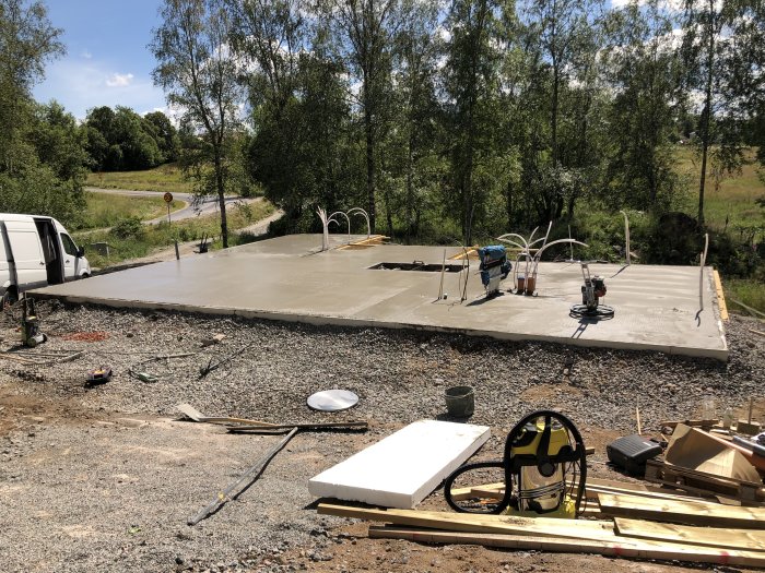Nybetonggjuten platta redo för polering med byggverktyg och material omkring på en byggarbetsplats.