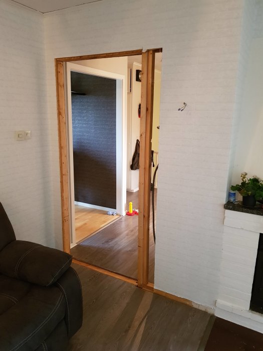 Delvis isågad dörröppning i vägg med exponerade trästolpar och kvarvarande dörrkarmsdelar.