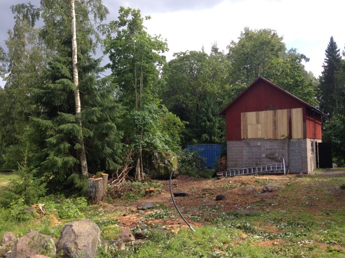 Tomt där en lada har rivits med kvarvarande verkstadsdel täckt av restvirke.