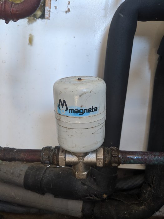 Magnetfilter installerat på en vattenledning i ett pumphus med logotypen "Magneta".