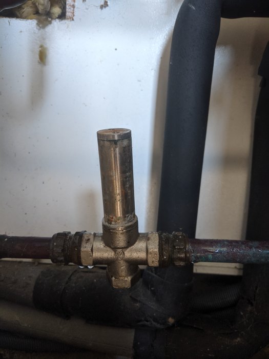 Ett magnetfilter installerat på en vattenledning i ett pumphus, visar tecken på användning och behov av rengöring.