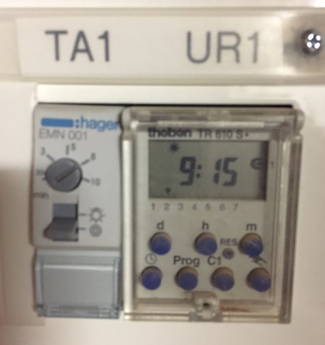 Hager EMD001 elektrisk timer med digital klocka visar 9:15, ring-symbol och kontrolllampor.