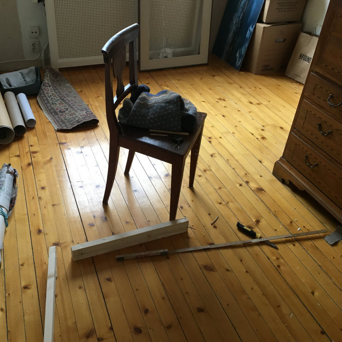 Gammalt massivt trägolv med synliga reparationer och röran från renovering i ett rum.