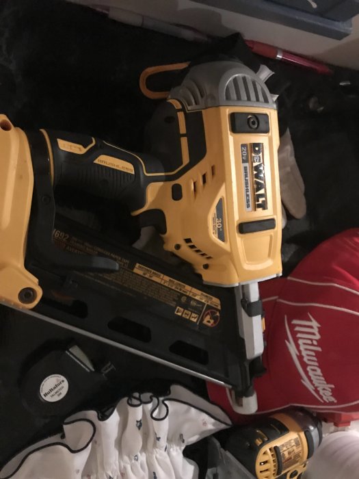 Dewalt spikpistol och en Milwaukee väska på en vit duk, arbetsverktyg efter användning i byggprojekt.