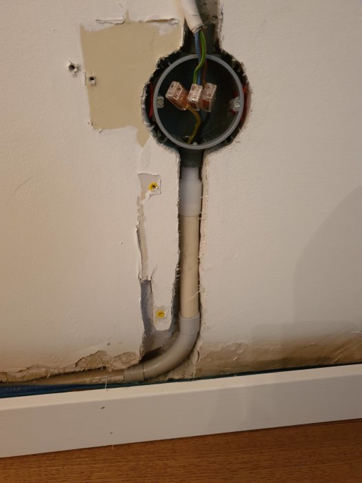 Kopplingsdosa med böjt vp-rör på vägg och kabelrör framsticker, beredd för fräsning och kabeldragning.